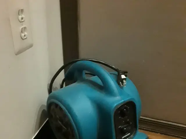 Air mover drying a wet floor after an appliance leak